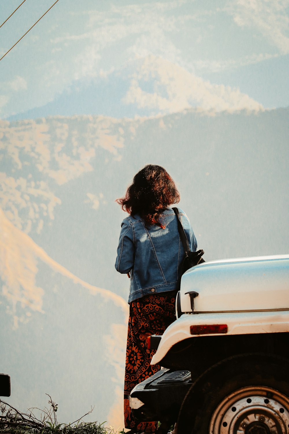 a woman standing on top of a hill next to a car