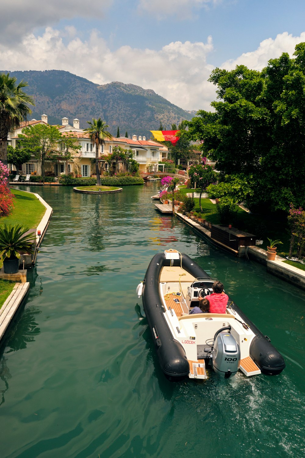 a boat traveling down a river next to a lush green hillside