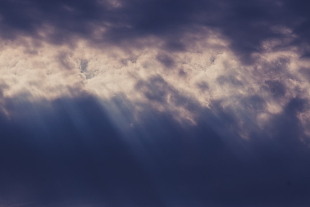 a plane flying through a cloudy blue sky