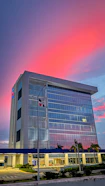 A vibrant commercial building with glass facades reflecting a bustling Indian cityscape at dusk.