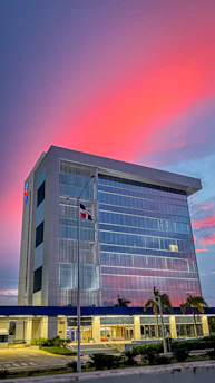 A vibrant commercial building with glass facades reflecting a bustling Indian cityscape at dusk.