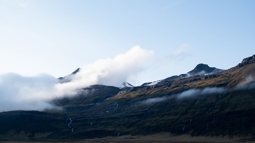 a mountain covered in fog and clouds on a sunny day