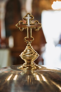 Close-up of a finely detailed churrigueresque golden cross with intricate floral patterns on a black velvet background.