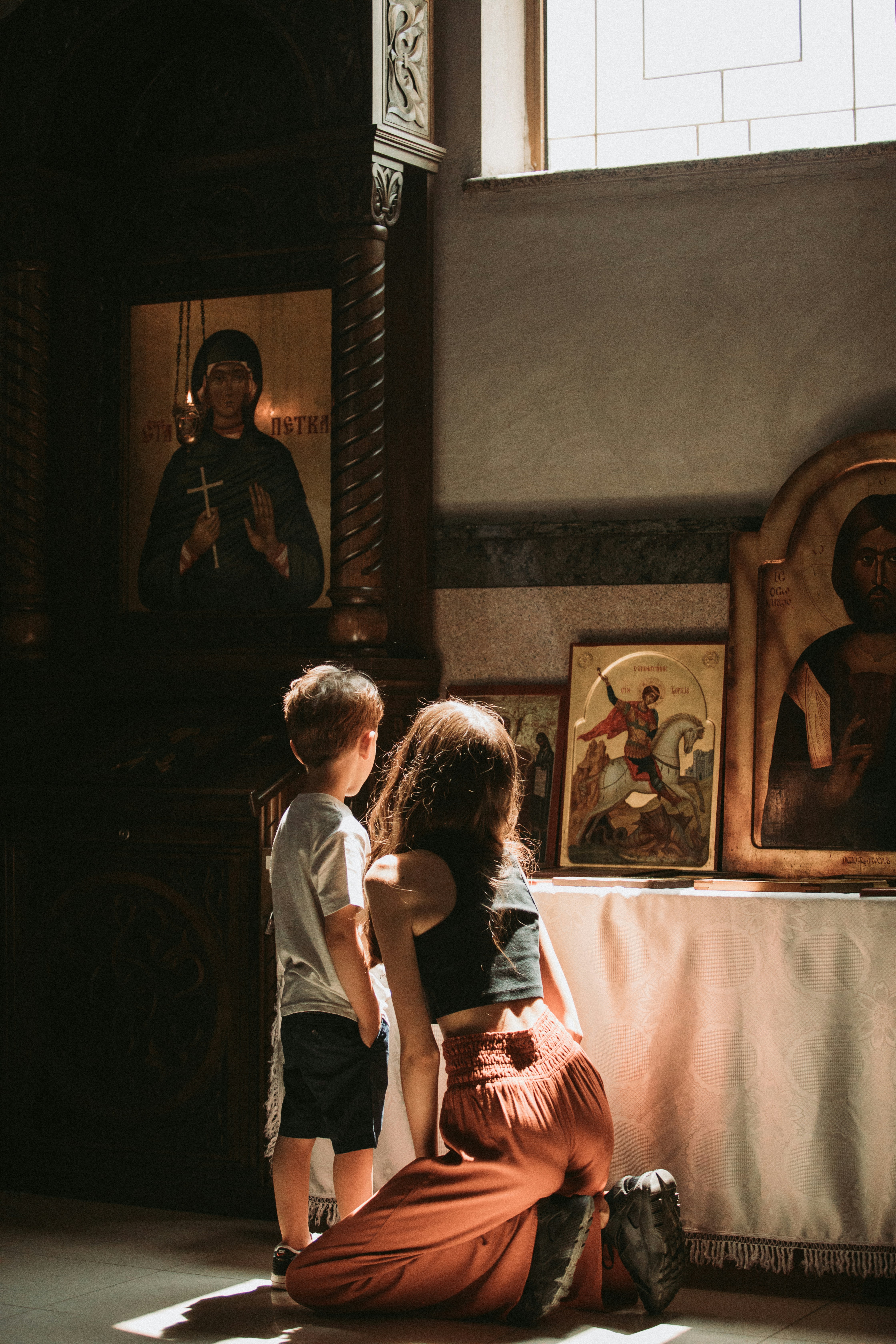 A peaceful moment of prayer with a mother and child by a window.