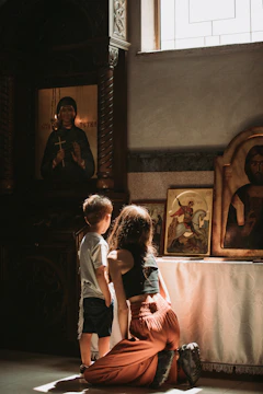 A mother reading a devotional with her child in a sunlit room.