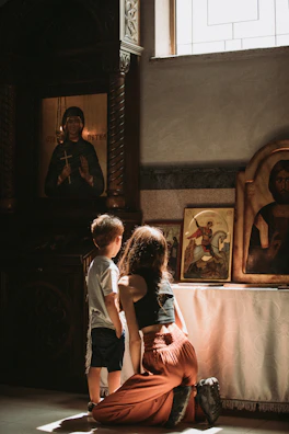 Parents kneeling by their children’s beds, gently praying with golden sunlight filtering through.
