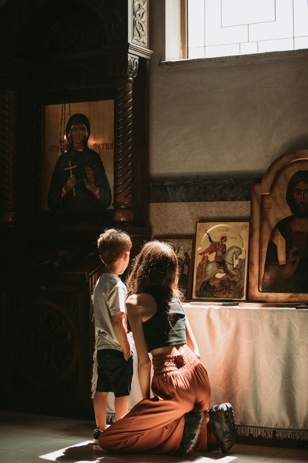 a woman kneeling down next to a little boy