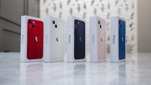 A lineup of colorful iPhones arranged side by side on a white surface.