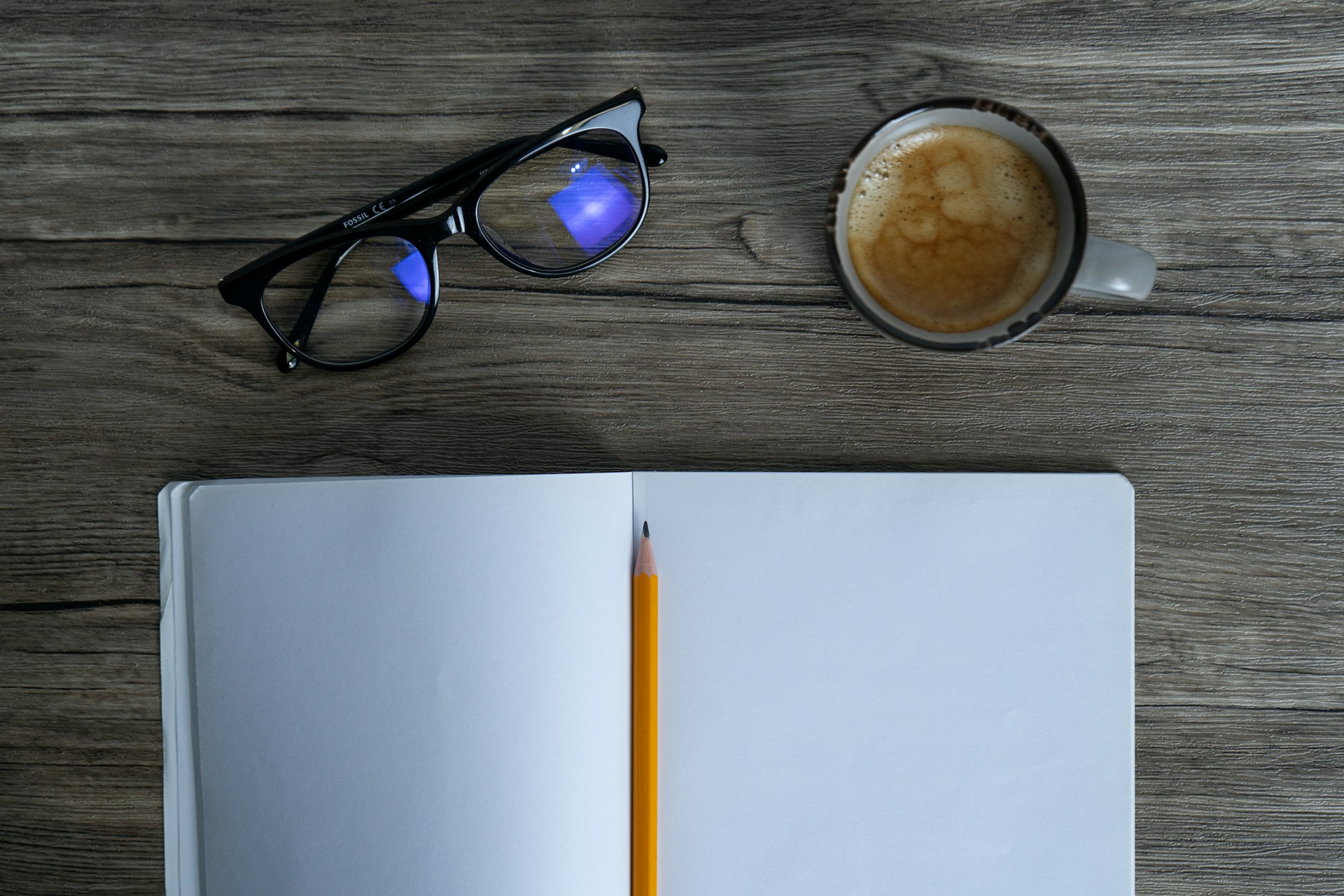 an open notebook with a pencil and a cup of coffee