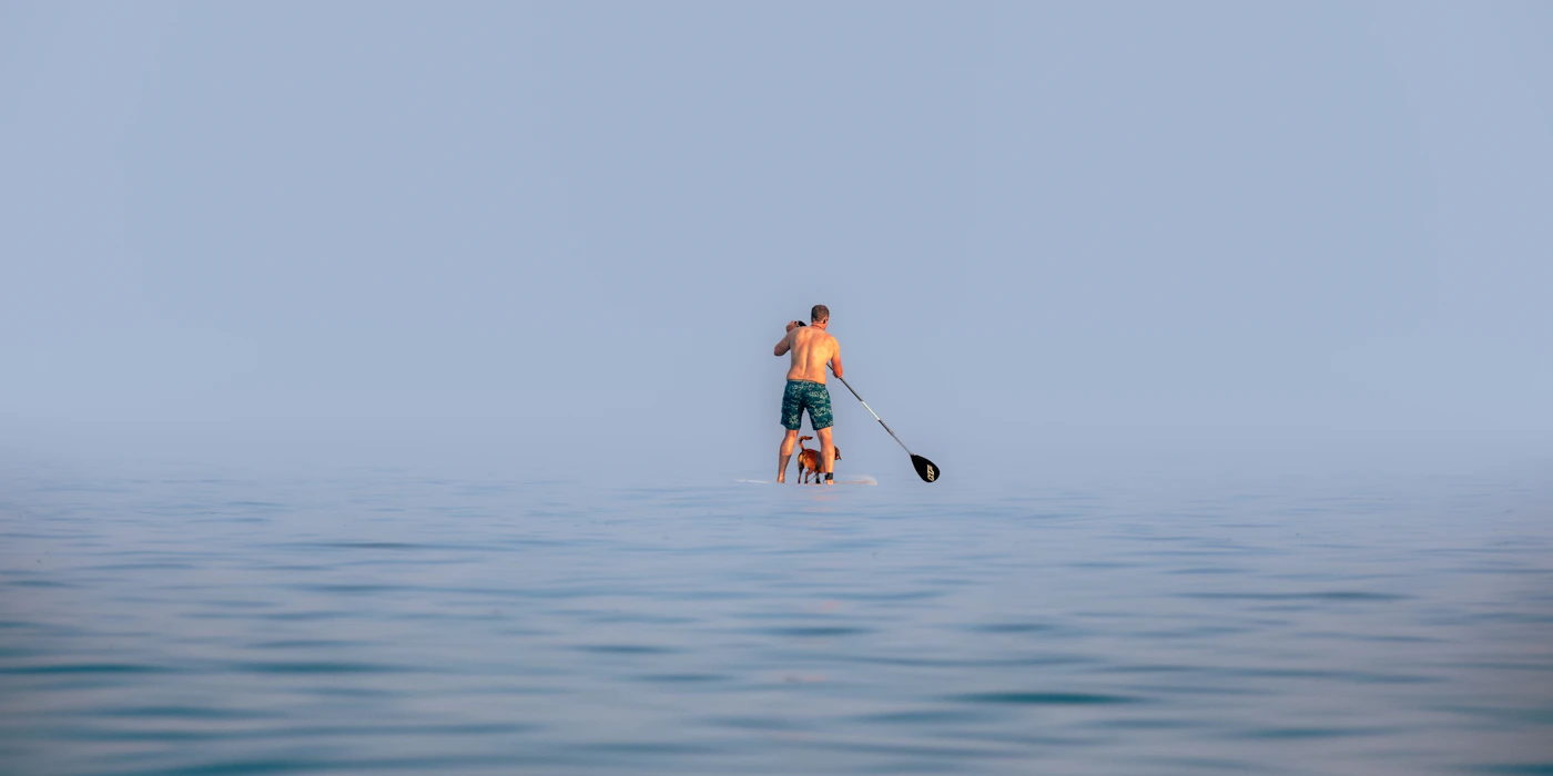 Paddleboarder moving across calm open water