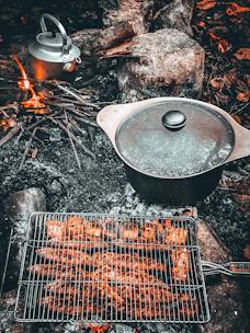 A family gathered around a campfire enjoying a meal prepared from custom preserved family recipes.