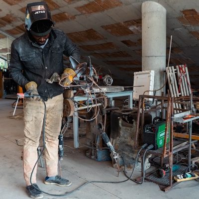 a man in a black jacket working on a piece of metal