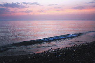 A serene coastline at sunset with gentle waves touching the shore, symbolizing calm and connection.