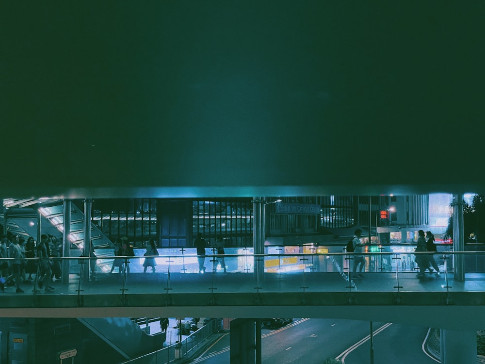 a group of people walking across a bridge at night