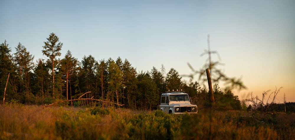 a truck parked in a field with trees in the background