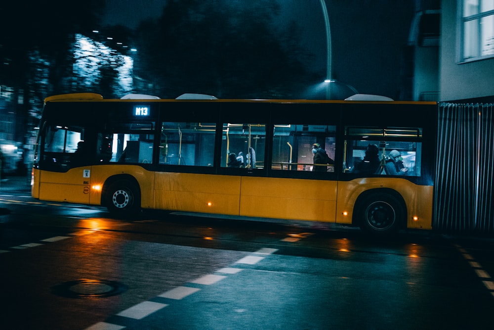 a yellow bus driving down a street at night