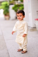 A toddler exploring nature in colorful ethnic wear and sandals.