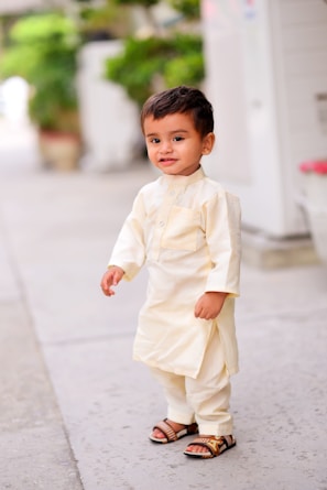 A toddler exploring nature in colorful ethnic wear and sandals.