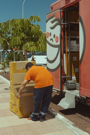 Close-up of hands packaging an order with orange and gray branded materials.