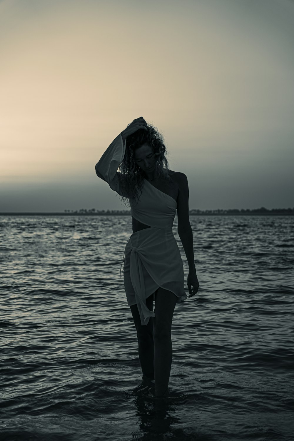 a woman in a white dress standing in the water