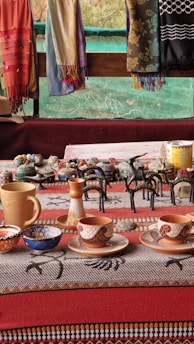 A colorful display of handcrafted pottery arranged on a rustic wooden table with earthy tones.