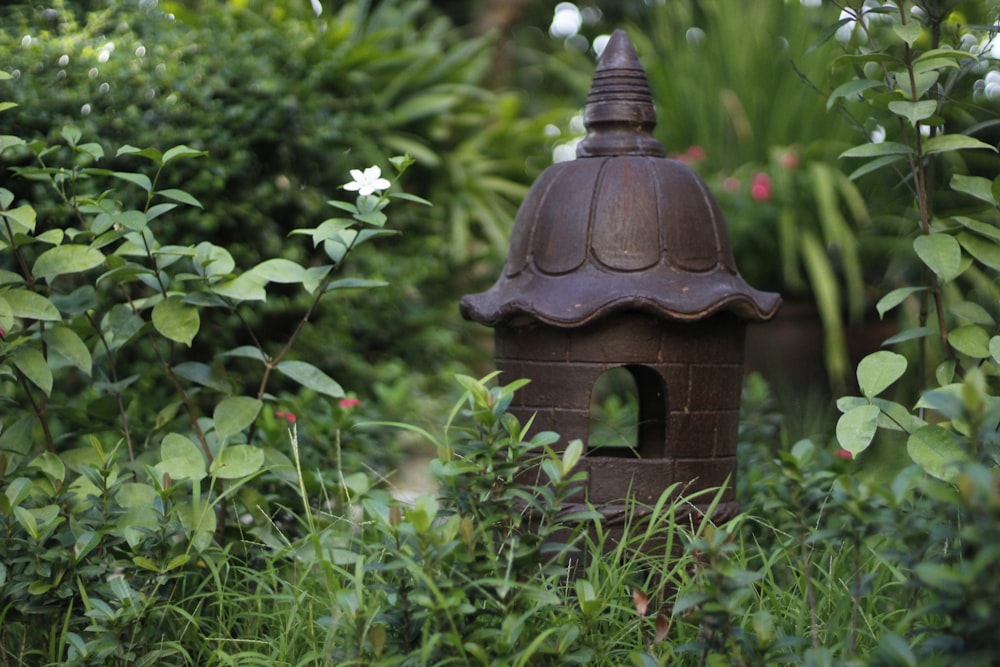 a bird house sitting in the middle of a garden