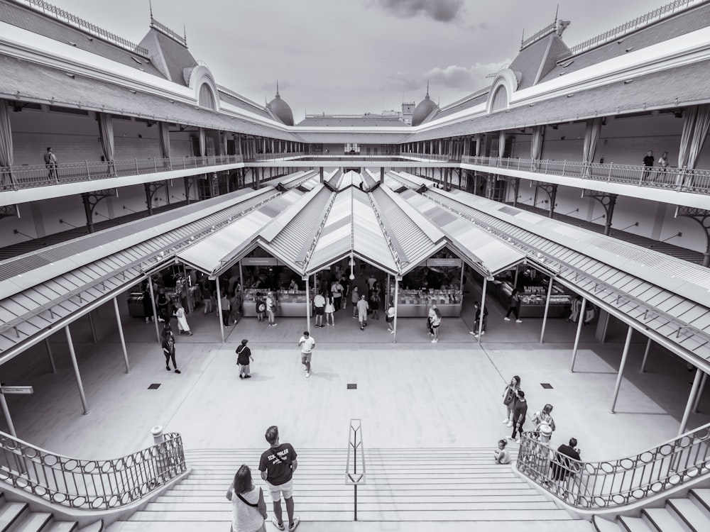 a black and white photo of people walking around a building