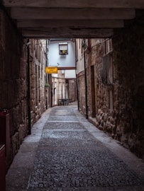 a narrow alley way with a yellow sign hanging from the ceiling