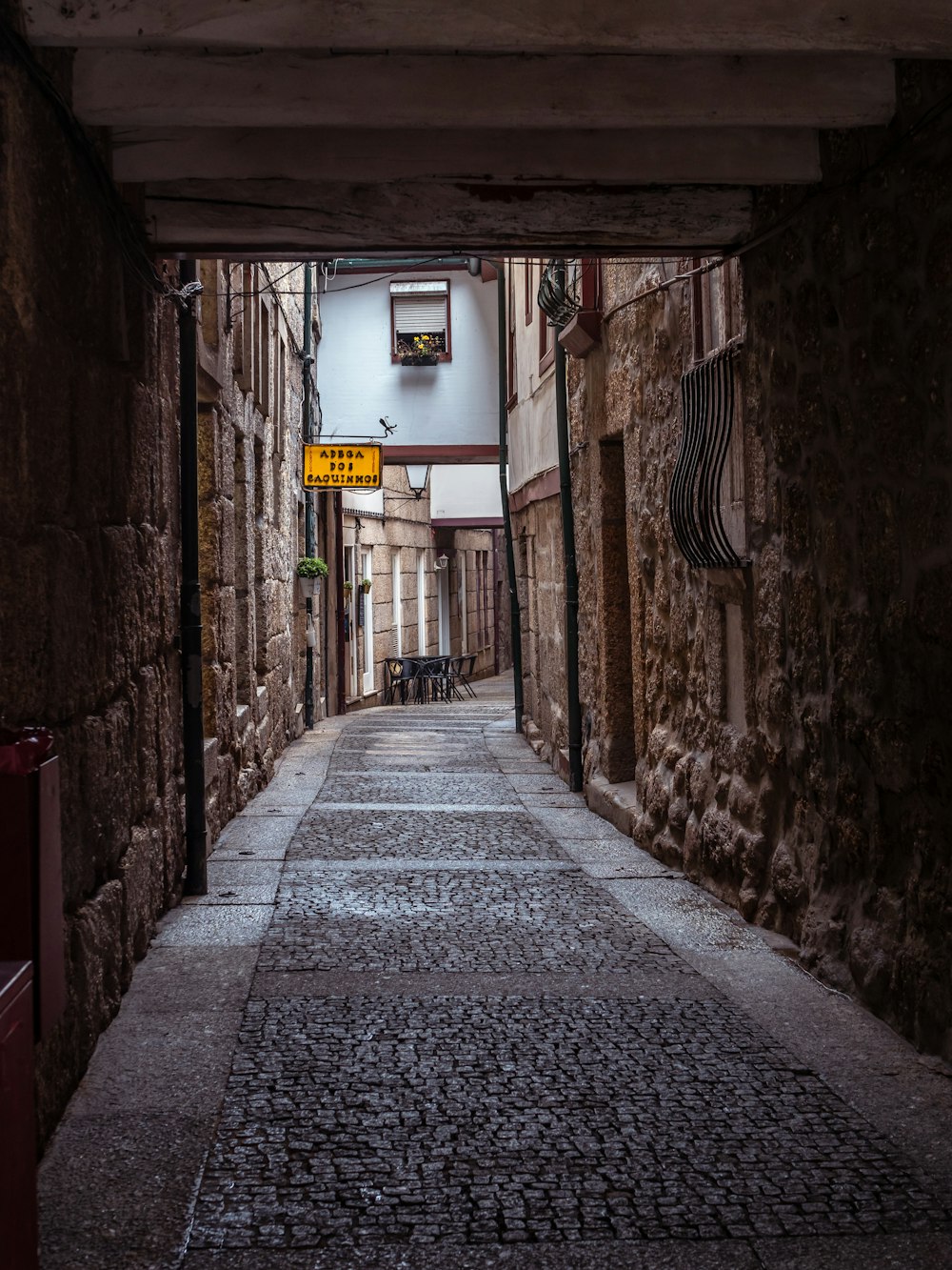 a narrow alley way with a yellow sign hanging from the ceiling
