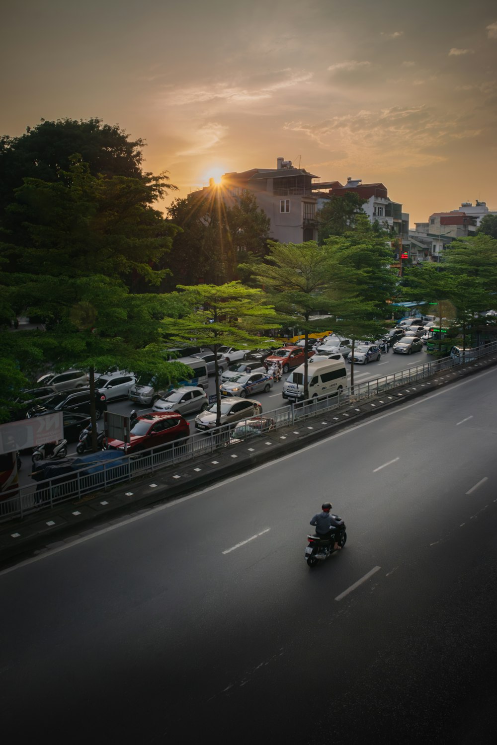 a man riding a motorcycle down a street next to a parking lot