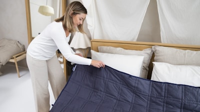 a woman putting a blue blanket on top of a bed