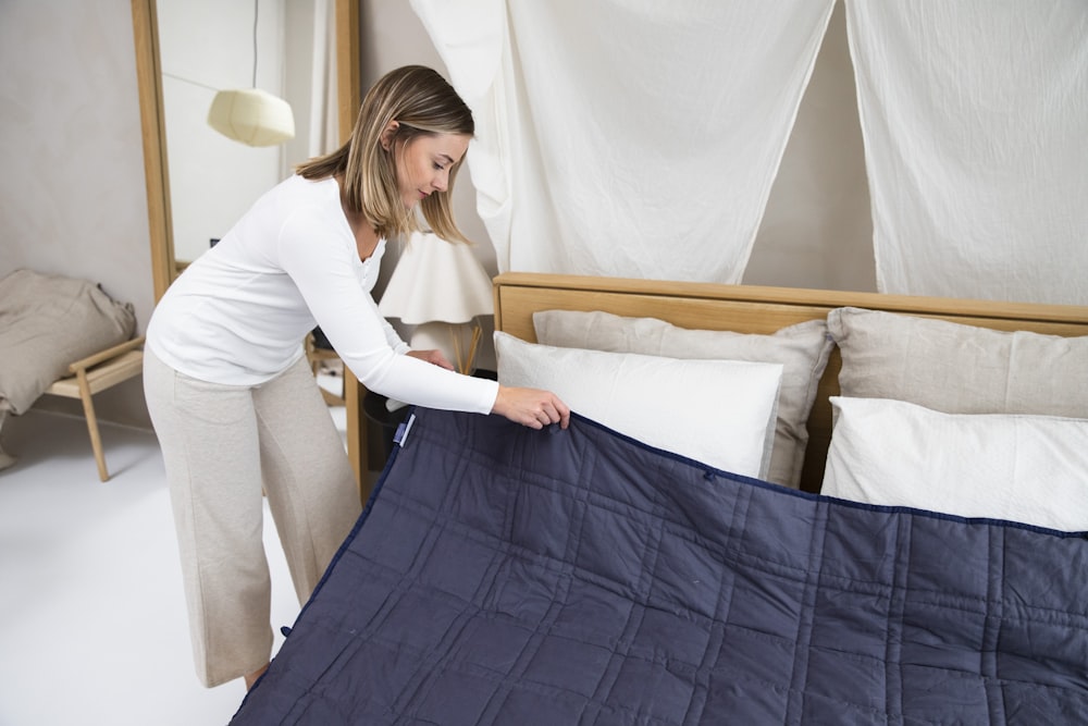 a woman putting a blue blanket on top of a bed