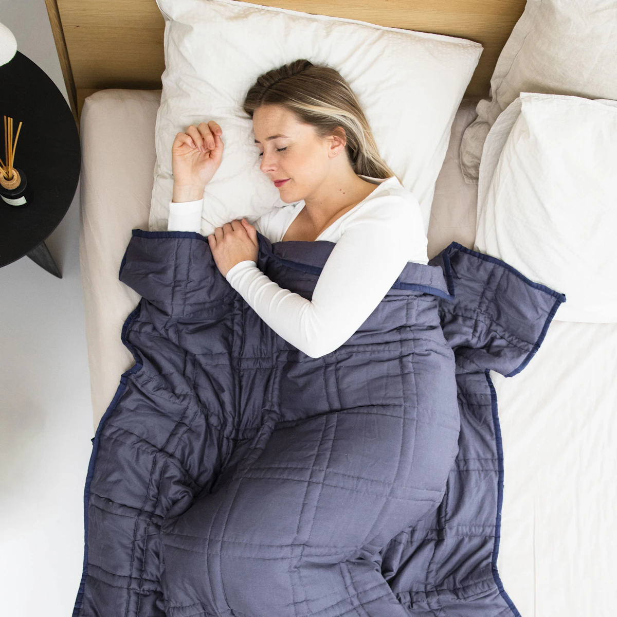 Vrouw ontspant liggend in bed na vagusstimulatie, klaar voor een diepe en herstellende nachtrust