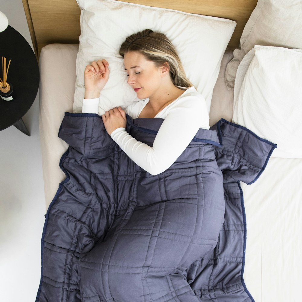 a woman laying in a bed with a blue blanket