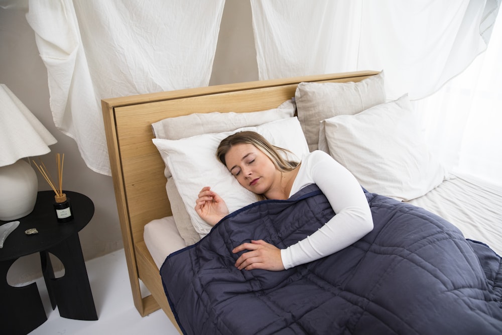 a woman laying in bed with a blue comforter