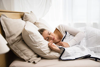 a woman sleeping in a bed with a white comforter