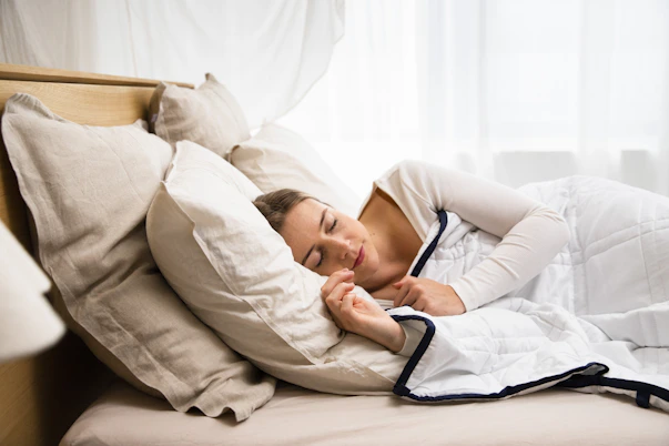 a woman sleeping in a bed with a white comforter