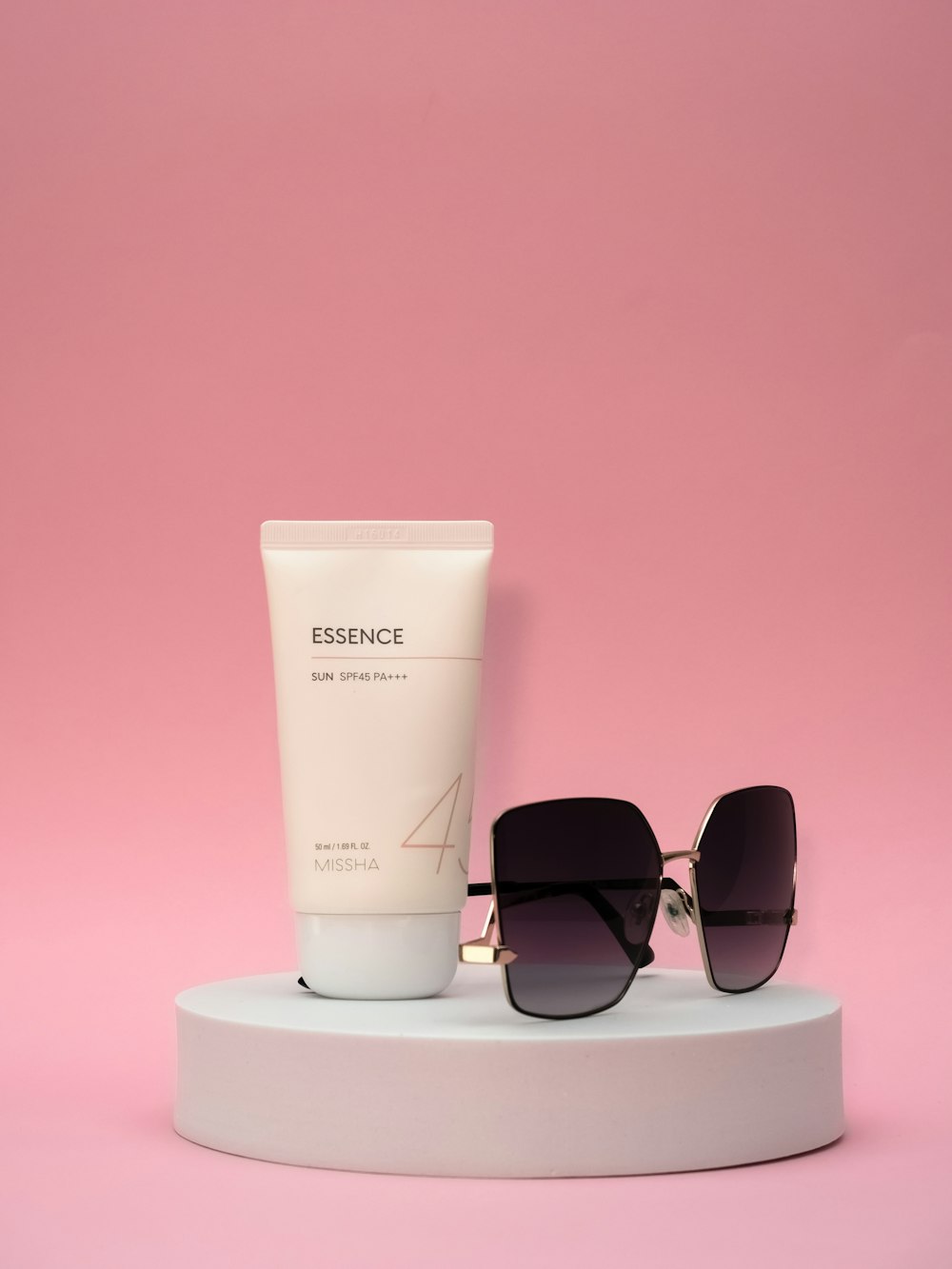 a pair of sunglasses, a tube of sunscreen and a tube of sunscreen
