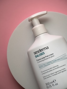 A bottle of foamy soap-free cream from the brand Sesderma is placed on a round white surface. The bottle is predominantly white with teal and black text, and includes product details and ingredients.
