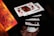 A series of playing cards appear to be floating in mid-air, capturing a dynamic moment possibly from a magic trick or cardistry performance. The cards are fanned out, aligning symmetrically as a hand beneath adds a sense of motion. The focus is sharp on the cards, highlighting their detailed patterns and suits.
