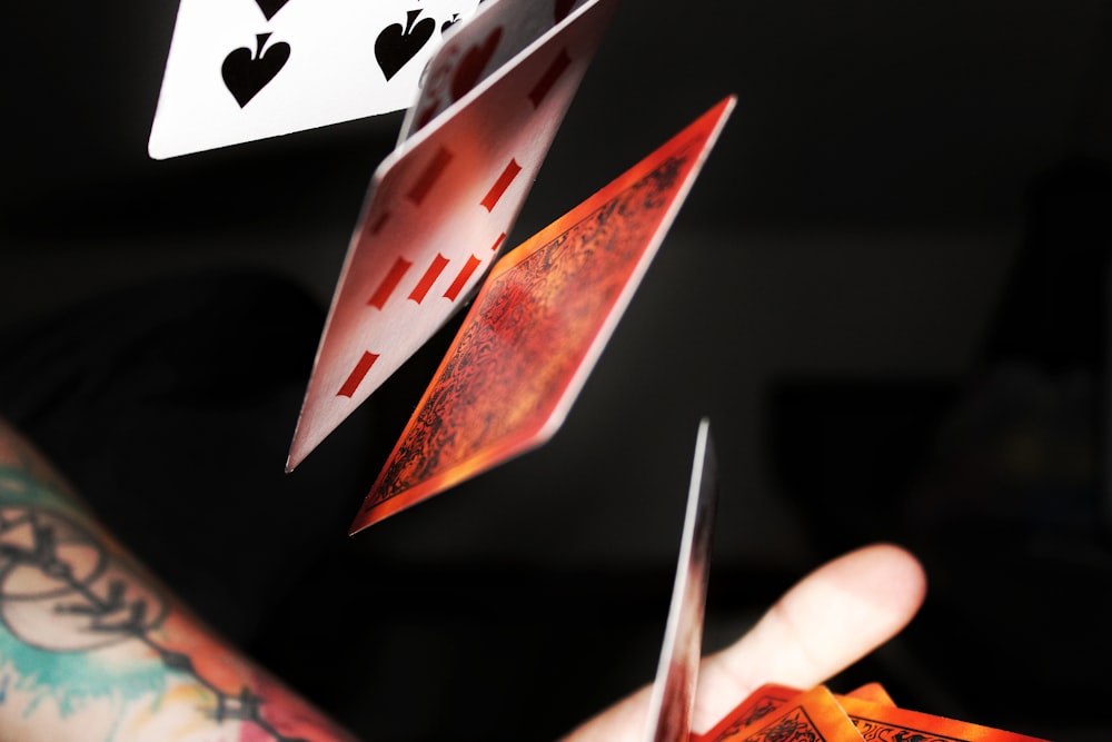 a person holding up playing cards in their hand