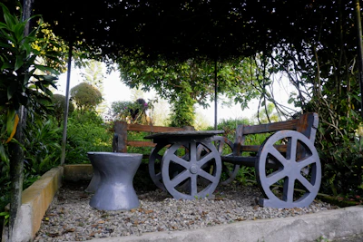 A rustic wooden bench stool placed beside a blooming garden path.