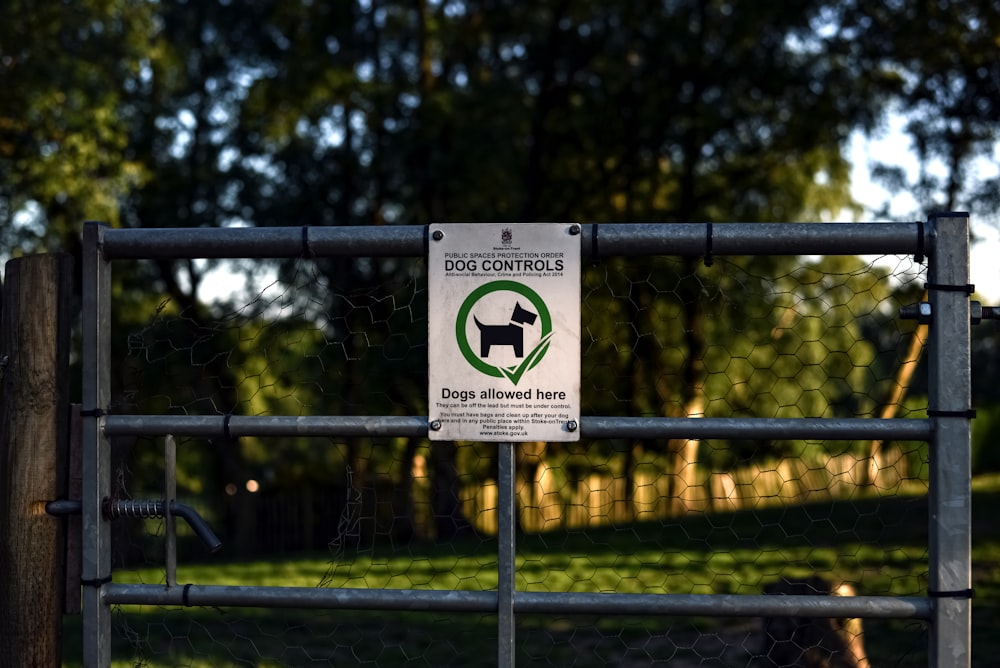 a dog control sign on a fence in a park