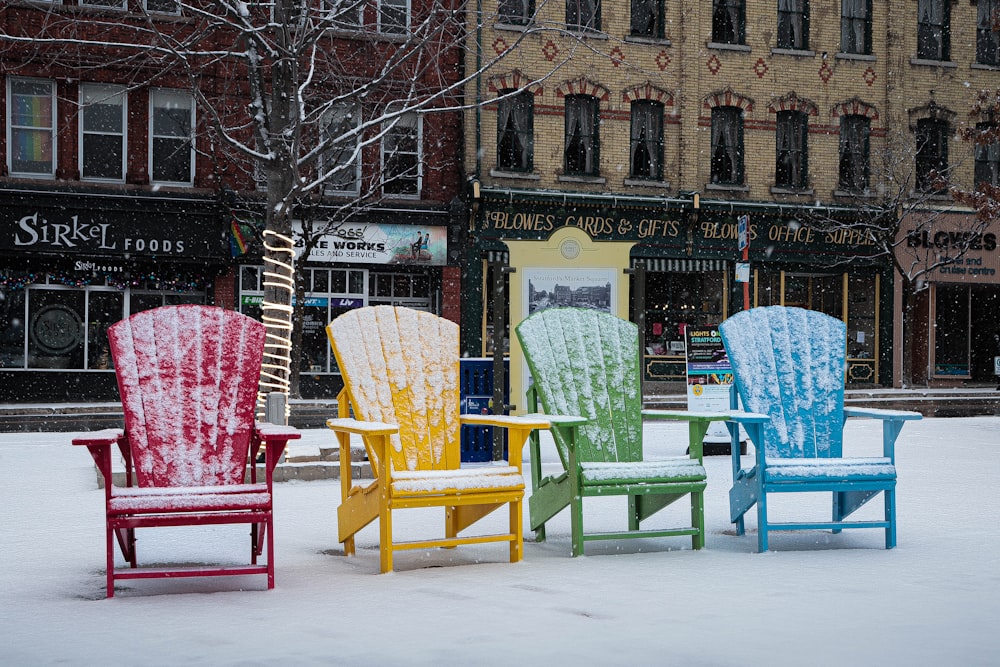 a row of colorful chairs sitting on top of snow covered ground