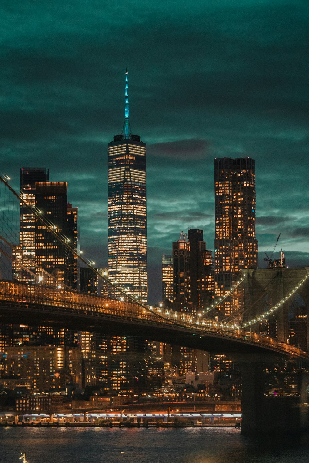 a city skyline at night with a bridge in the foreground