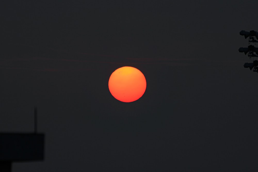 a bright orange ball of sun in the dark sky
