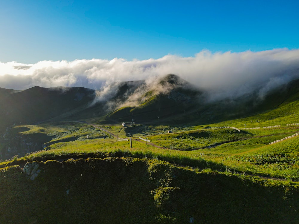 a lush green hillside covered in fog and clouds