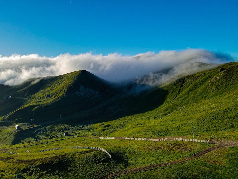 a lush green hillside covered in clouds and grass