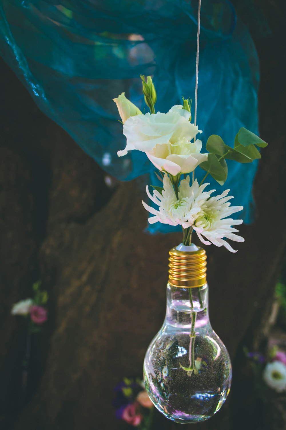 a light bulb hanging from a string with flowers in it