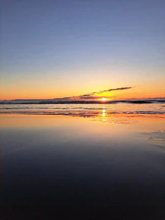 A peaceful sunset over a calm sea with a subtle nebula blue sky, symbolizing hope